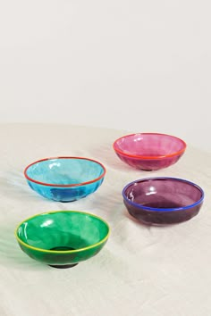 four colorful bowls sitting on top of a white table