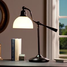 a desk lamp sitting on top of a table next to a book shelf and window