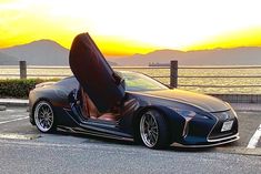 a black sports car parked on the side of the road with its doors open at sunset