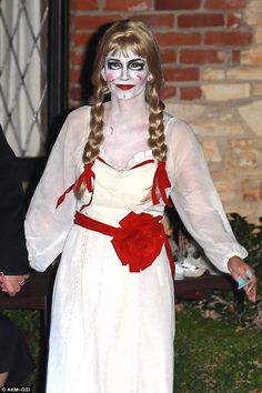 a woman dressed in white and red is holding hands with a man wearing black makeup