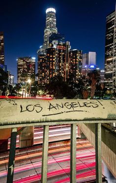 the city skyline is lit up at night, with graffiti written on the railings