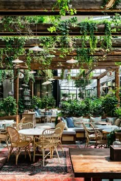 an outdoor dining area with tables, chairs and potted plants hanging from the ceiling