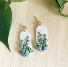 the earrings are decorated with green and white flowers