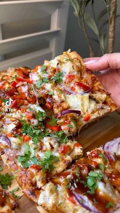 someone taking a slice of pizza from a wooden cutting board on top of a table