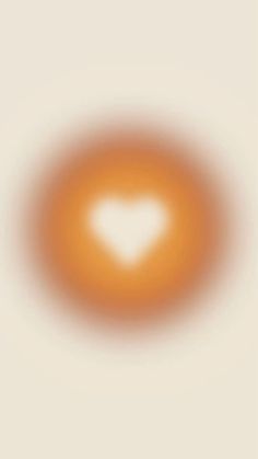 an orange circle with a white heart in the center on a beige background that appears to be blurry