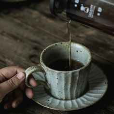 a person is pouring coffee into a cup