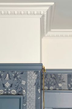 an ornate blue and white wallpaper in a kitchen with gold trim on the door