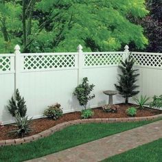 a white fence with trees and plants around it