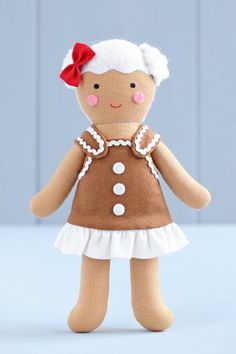 a little doll with a red bow on her head and dress is standing in front of a gray wall