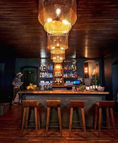 a bar with stools and lights hanging from the ceiling