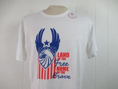 "Vintage 1990s or 2000s t-shirt. Made of white cotton with red, white and blue patriotic graphics. Reads: Land of the free home of the brave. Has U.S. Air Force style logo. Size large. Actual measurements are: 44\" around the chest 44\" around the waist 19.5\" shoulder seam to shoulder seam 29\" overall length In excellent unused condition. New old stock." Red Americana T-shirt With American Flag, White Americana T-shirt For 4th Of July, White Americana Letter Print T-shirt, American Style White Tops For 4th Of July, Americana T-shirt With American Flag For 4th Of July, White American Flag T-shirt For Independence Day, White Americana T-shirt With American Flag, White T-shirt With American Flag For Independence Day, White Americana T-shirt For Summer