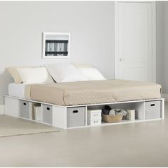 a bed with storage drawers underneath it in a room that has white walls and floors