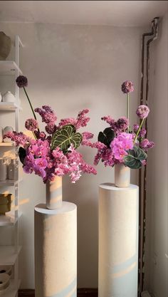 two white vases with purple flowers in them