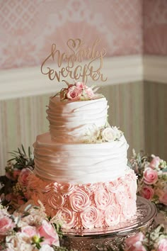 a wedding cake with pink flowers on top and the words happily ever after written on it