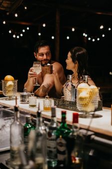 two women and a man sitting at a bar with drinks in front of the counter