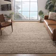 a living room with a couch, chair and rug in front of a large window