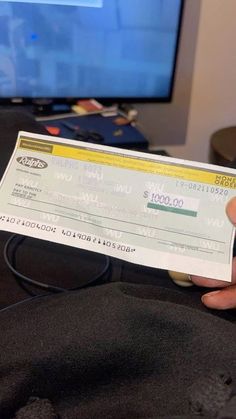 a person holding up a large check in front of a tv