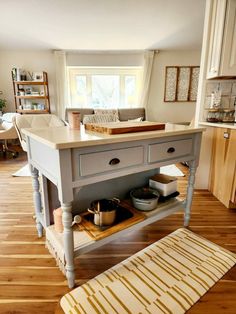 a kitchen island in the middle of a living room with an area rug on the floor