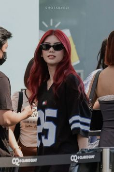 a woman with red hair and sunglasses standing next to a man in a black shirt