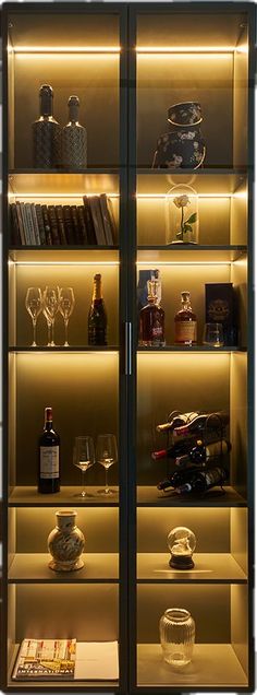 an illuminated display case with many bottles and glasses on the shelves in front of it