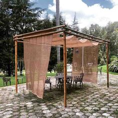 a gazebo sitting on top of a stone ground next to a table and chairs