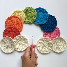 the crocheted circles are arranged in different colors and sizes, with one person holding a pair of scissors