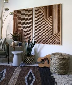 a living room with two paintings on the wall next to a guitar and potted plant