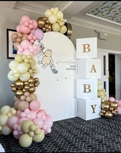 balloons are arranged in the shape of a baby's name and balloon arch with gold, pink, and white balloons