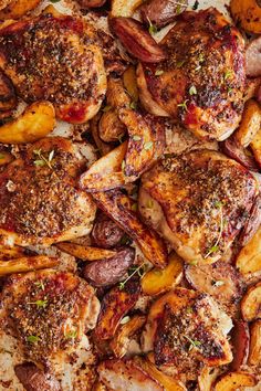 chicken and potatoes on a baking sheet covered in seasoning sprinkled with herbs