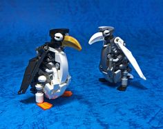 two lego penguins standing next to each other on a blue surface with one penguin holding a knife