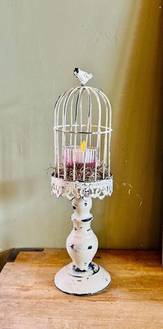 a white birdcage filled with candles sitting on top of a wooden table