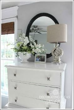 a white dresser with flowers and a mirror