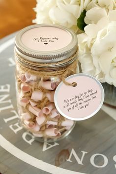 a jar filled with pink and white candies on top of a table next to flowers