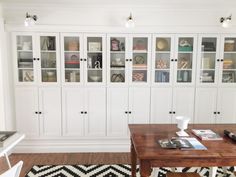 a living room with white bookcases and black and white rug