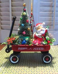 a christmas tree in a red wagon with santa clause on top and other decorations around it