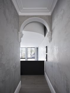 an empty hallway with white walls and wood flooring is seen in this image from the entrance