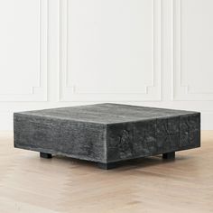 a black square table sitting on top of a hard wood floor next to a white wall