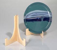 a blue and white plate sitting on top of a wooden stand next to a glass bowl