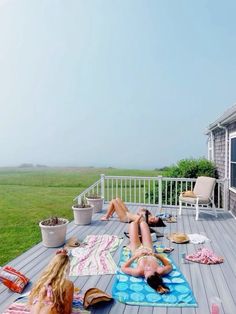 two women laying on a deck with towels