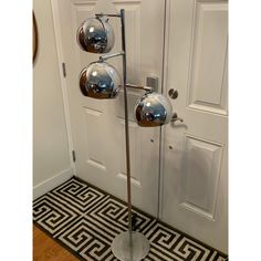 three chrome balls on a metal pole in front of a door with a black and white rug