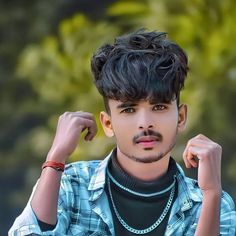 a young man with black hair wearing a blue and white shirt is posing for the camera