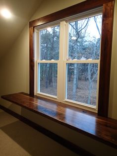 an empty room with a large window and wooden bench in front of the windowsill