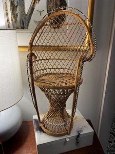 a wicker chair sitting on top of a table next to a lamp and pictures