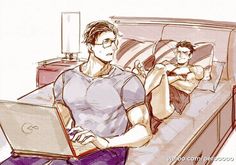 a man sitting on a bed with a laptop in front of him and another person laying down next to him