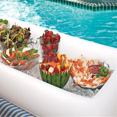 fruit salads and watermelon bowls on an inflatable raft next to a swimming pool