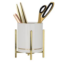 a white cup with gold handles holding scissors and utensils, on a stand