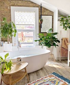 the bathroom is decorated in white and has plants on the windows sill, along with a large bathtub