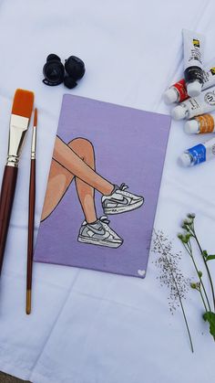 some art supplies are laying out on a white table with paint, brushes and flowers