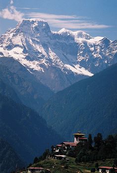 the mountains are covered in snow and there is a small village on the hill below