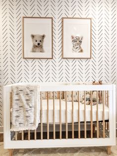 a baby crib with two pictures on the wall and a teddy bear hanging above it